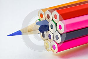 Colored pencils, ends are not sharpened, blue pencil sharpener, on white background, selective focus