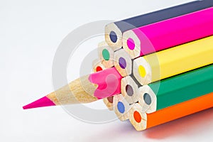Colored pencils, ends are not sharpened, pink pencil sharpened, on white background, selective focus
