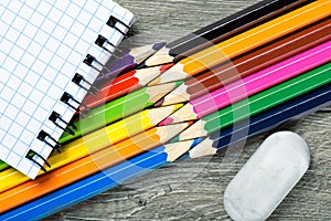 colored pencils, eraser, notebook closeup on wooden table