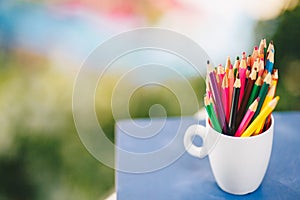 Colored pencils in a glass on Bokeh background