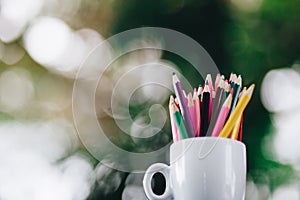 Colored pencils in a glass on Bokeh background