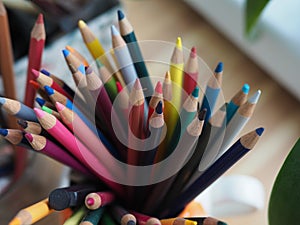 colored pencils are in a glass on the table in a creative mess
