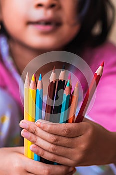 Colored pencils held by little girl in blur