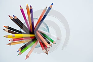 Colored pencils kept in glass on white background