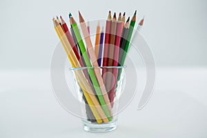 Colored pencils kept in glass on white background