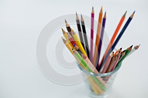 Colored pencils kept in glass on white background