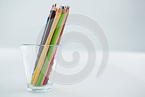 Colored pencils kept in glass on white background