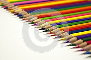 colored pencils lying in row on white background