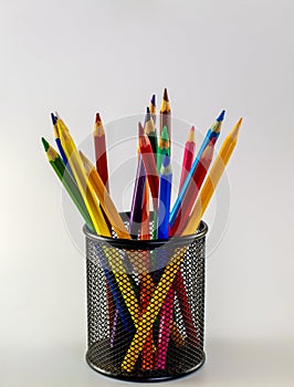 Colored pencils in mesh pencil holder. Isolated, copy space for text.