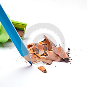 Colored pencils and metal sharpener, colored pencil filings isolated on a white background, close-up, space for text