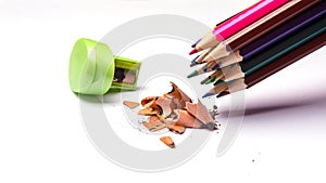 Colored pencils and metal sharpener, colored pencil filings isolated on a white background, close-up, space for text