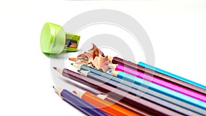 Colored pencils and metal sharpener, colored pencil filings isolated on a white background, close-up, space for text