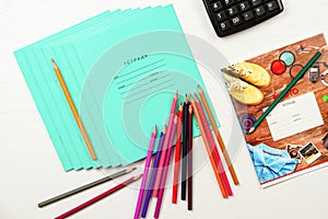 colored pencils and notebooks diary lie on a white wooden table