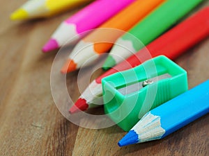 Colored pencils and sharpener on wooden background