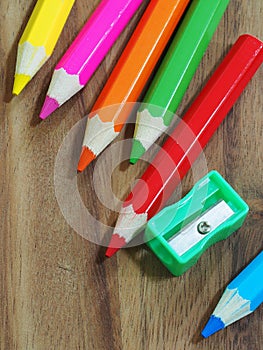 Colored pencils and sharpener on wooden background