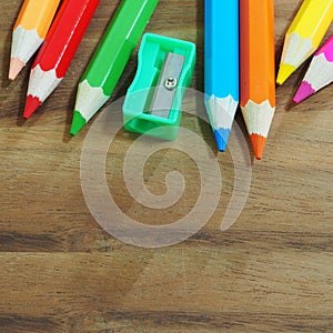 Colored pencils and sharpener on wooden background