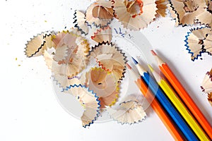 Colored pencils on a white background. Shavings from colored pencils