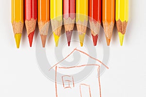 Colored pencils on a white sheet of paper on which the house is painted. Pencils red and yellow on a white background