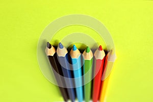 Colored pencils on a yellow background. 6 colors: Black, blue, blue, green, red, yellow. Pencils are well-honed. Flatlay. Isolated