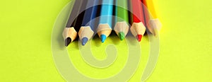 Colored pencils on a yellow background. 6 colors Black, blue, blue, green, red, yellow. Pencils are well-honed. Flatlay. Isolated