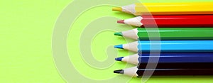 Colored pencils on a yellow background. 6 colors Black, blue, blue, green, red, yellow. Pencils are well-honed. Flatlay. Isolated