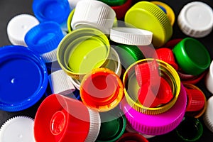 Colored PET caps on a black background. Recycled plastic bottle caps. Separate garbage collection. Recycling of plastic for