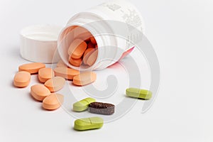 Colored pills spilling out of a bottle on white background