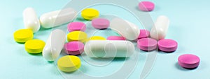 Colored pills and tablets on green background. Close up. Medical treatment concept