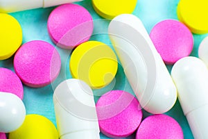 Colored pills and tablets on green background. Close up. Medical treatment concept