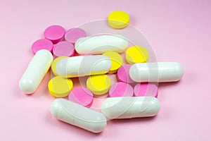 Colored pills and tablets on pink background. Close up. Medical treatment concept