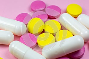 Colored pills and tablets on pink background. Close up. Medical treatment concept