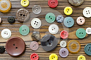 Colored plastic buttons on brown wooden background