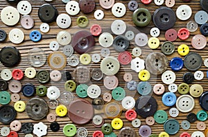 Colored plastic buttons on brown wooden background