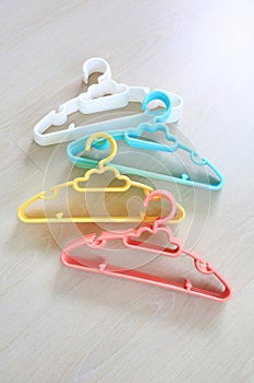Colored plastic Clothes Hangers on wooden background
