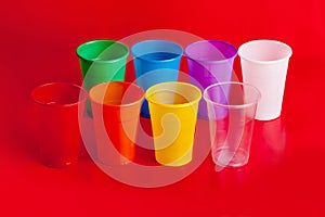 Colored plastic cups on red background