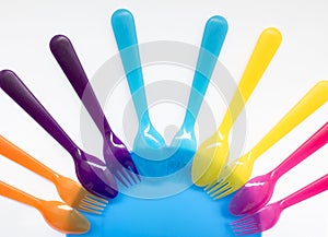 Colored plastic forks and spoons , on a plate, the background on