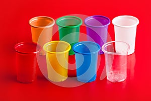 Colored plastic glasses on red background