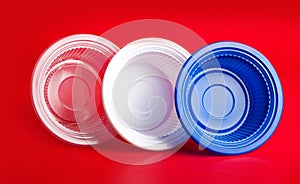 Colored plastic plates on red background