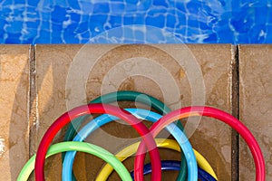 Colored plastic rings on the mosaic of the edge of a swimming po photo