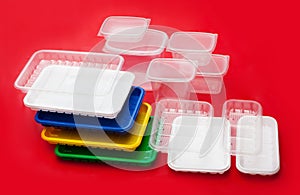Colored plastic utensils on red background