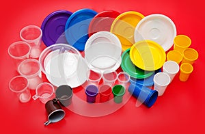 Colored plastic utensils on red background