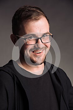 Portrait of smiling man in black t-shirt on gray studio background posing to the camera
