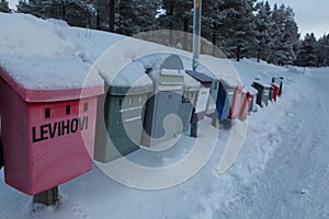 Colored post boxes line covered by snow in Levi, Finland