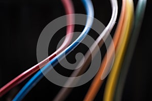 Colored power cables against a dark background that come from a transformer