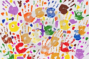 Colored prints of children`s hands on a white canvas. A child`s handprint on paper. Colored handprints. Many children`s multi-