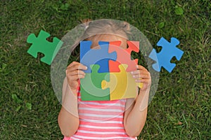 Colored puzzle made of elements in the hands of child suffering from autism