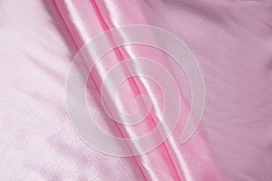 Colored rose textile satin fabric folded in folds and waves with highlights and texture