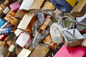 Colored rusted padlocks chained on a bridge handrail. Romantic