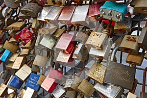 Colored rusted padlocks chained on a bridge handrail. Romantic