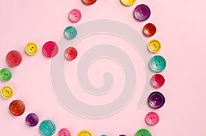 Colored sewing buttons composition on pink background